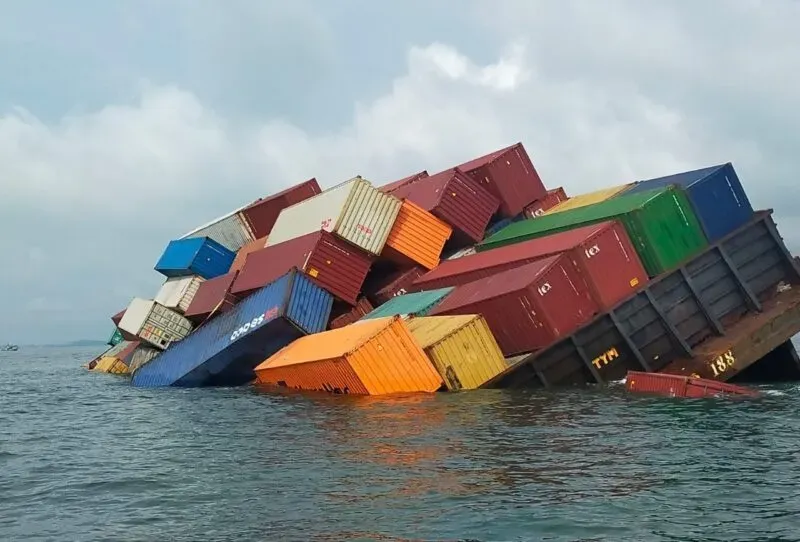 Capsized cargo vessel with its stacked containers tumbling into the sea